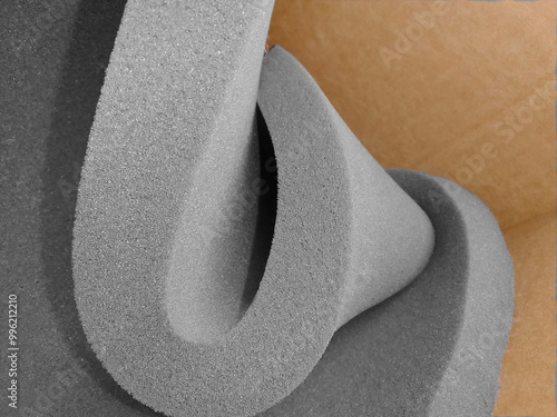 one roll of gray sponge foam material on brown cardboard background