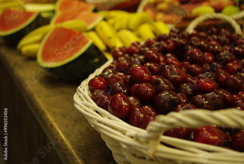 Diferentes frutas con cesta de cerezas en primer plano, detalle de surtido de fruta en un mercado, alimentación saludable y ecológica