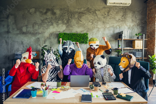 Photo of rooster gorilla lion sloth zebra panda raccoon mask people laptop desk raise fists celebrate loft interior office indoors