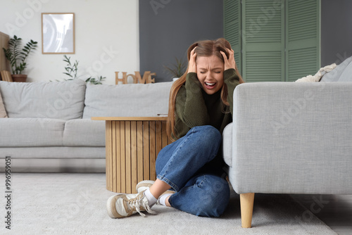 Young woman having panic attack near sofa at home