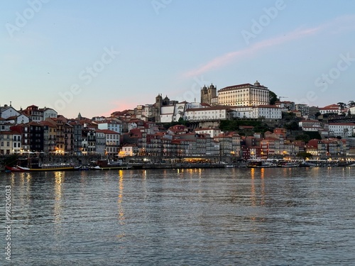 A captivating view from Vila Nova de Gaia across the Douro River, showcasing Porto's vibrant, colorful buildings glowing under the warm hues of a stunning sunset.