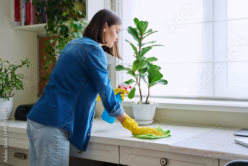 Young woman cleaning room, dusting, cleaning with spray and cloth