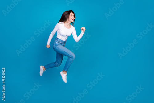 Full size photo of pretty teen girl running hurry black friday wear trendy white outfit isolated on blue color background