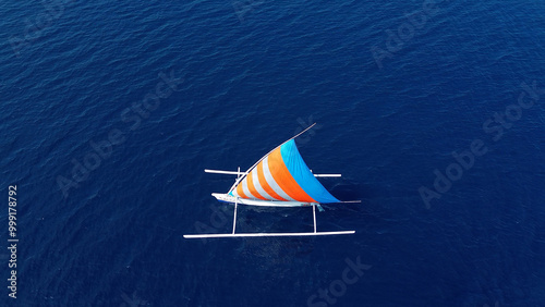 Indonesian fishing trimaran, traditional boat during fishing. Sailing trimaran in motion, drone view