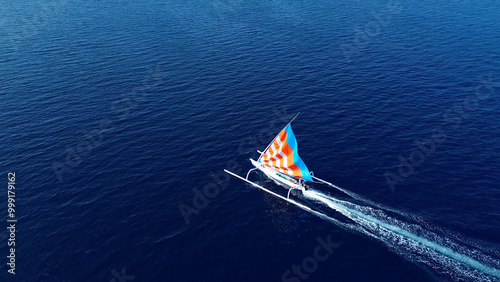 Indonesian fishing trimaran, traditional boat during fishing. Sailing trimaran in motion, drone view