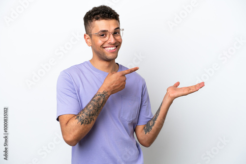 Young caucasian Brazilian man isolated on white background holding copyspace imaginary on the palm to insert an ad