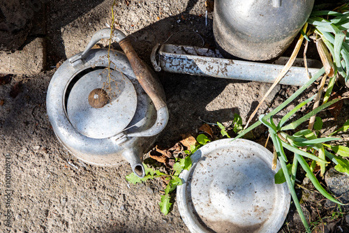 Old aluminum kettle near the garage outdoors.