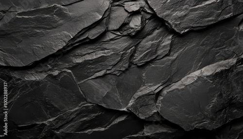 Close-up of textured black slate rock surface with natural cracks, perfect for background or design elements.