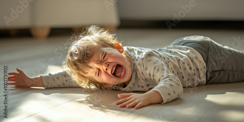 Unhappy toddler having a temper tantrum, lying on the floor and crying.