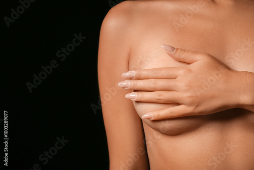 Naked young woman with beautiful breasts on black background, closeup