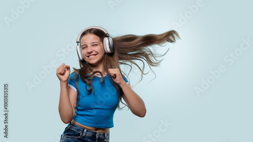 A young girl happily dancing with headphones, hair flying mid-movement.