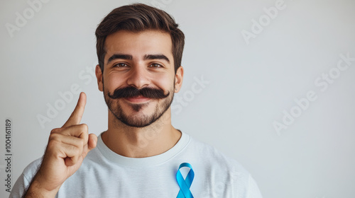 Smiling man with a styled mustache wearing a blue ribbon and pointing upward. Movember awareness and men's health campaign concept for design and print.