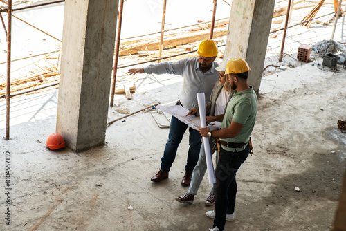 Two architects work together on-site, discussing blueprints and coordinating to bring their project to life. 