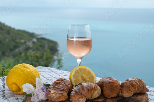 Italian desssert, Naples sfogliatella, shell-shaped layered pastry, with sweet custard-like filling made with semolina, ricotta, and candied citrus fruit and glass of ose wine and seaview