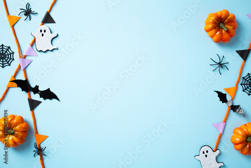 Halloween party decorations on pastel blue background. Frame of pumpkins, ghost, bats, spiders, and garland