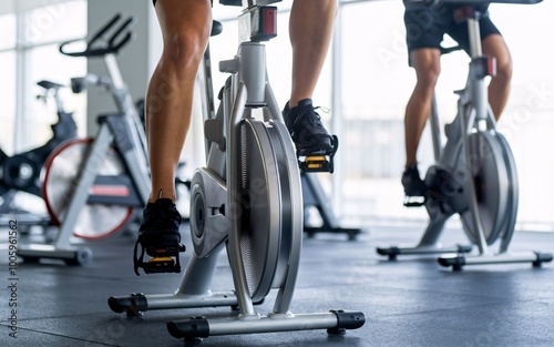 Close-up of people cycling on stationary bikes at a gym.