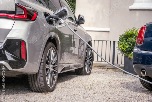 Electric car being charged outside at home in typical British suburban residential setting