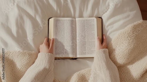 Hands gently clasped over an open Bible on a table, accompanied by a cup, conveying a moment of reflection and tranquility in soft, natural light