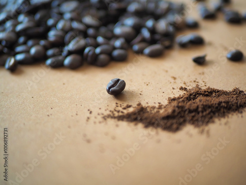 Auf einem hellbraunen Untergrund liegt ein Haufen Kaffeebohnen, eine einzelne Bohne liegt davor, daneben gemahlenes Kaffeepulver