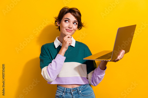 Portrait of pretty nice young girl hold laptop look empty space wear shirt isolated on yellow color background