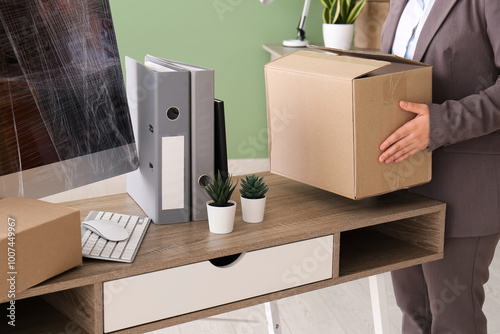 Businesswoman putting moving box on desk in office, closeup