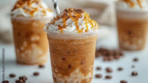 caramel frappuccino smoothie topped with whipped cream and caramel drizzle presented in a clear plastic cup with a straw isolated on a bright white background