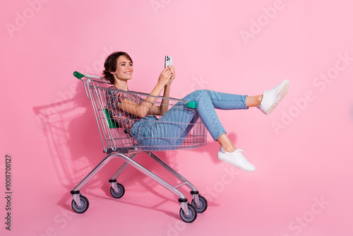 Photo of positive nice lovely girl wear stylish clothes sitting trolley reading post isolated on pink color background