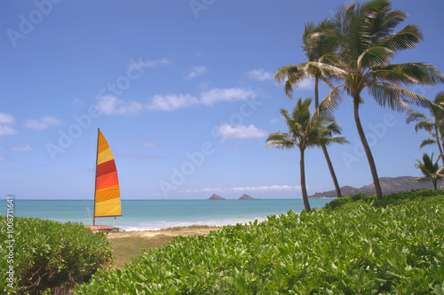 Colourful sailboat on the beautiful sandy Kailua Beach with the Mokulua Islands on the horizon, on the island of Oahu, Hawaii