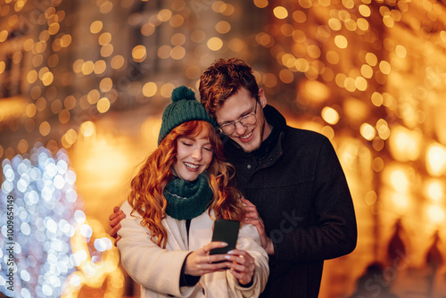 Happy couple taking selfies on city street on christmas or new year's eve.