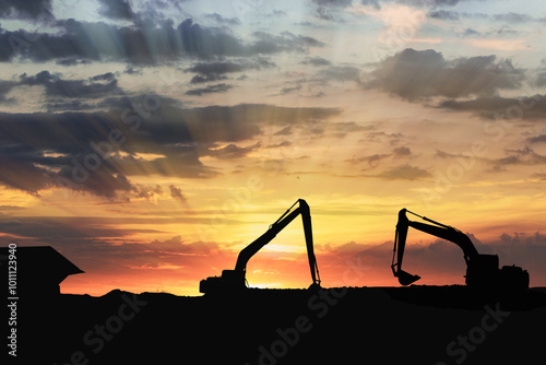 Crawler excavators silhouette are digging the soil in the construction site. on sunset background