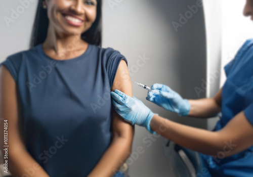 A woman smiles as she receives an injection in her upper arm from a medical professional.