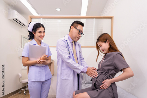 A doctor examining pregnant woman sitting on bed at clinic,a nurse holding document,standing beside,concept of pregnancy health, gynecology consultation and appointment