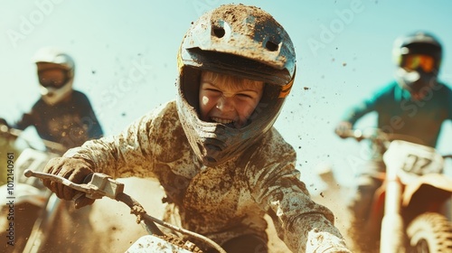 A young child, covered in mud, races a dirt bike intensely on a sunny day, encapsulating the thrill, focus, and adventurous spirit of off-road biking.