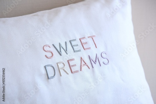 White pillow with embroidered 'Sweet Dreams' text in pastel colors