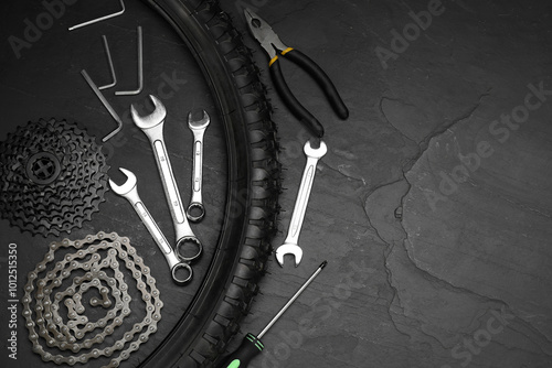 Parts of bicycle and tools on black table, flat lay. Space for text