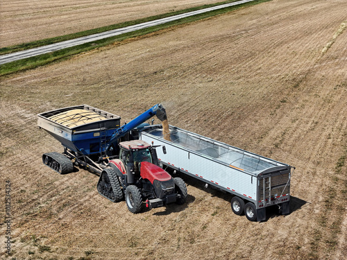 tracked tractor and grain cart loading soybeans into a grain truck for transport