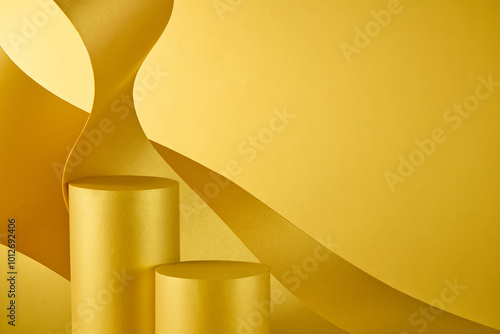 To create a classic feel against a bronze-gold backdrop, two cylindrical yellow platforms utilized for product placement are surrounded by wavy paper panels.