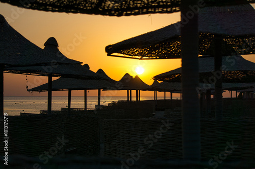 Close-up of beach umbrellas - beautiful setting sun in the background. Beach on the Red Sea, Egypt