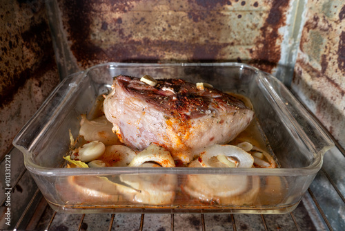 Roast lamb shoulder seasoned with paprika, garlic, onion, salt, pepper, and thyme, cooking in a Pyrex dish in the oven. Golden, flavorful, and ready for a delicious meal.