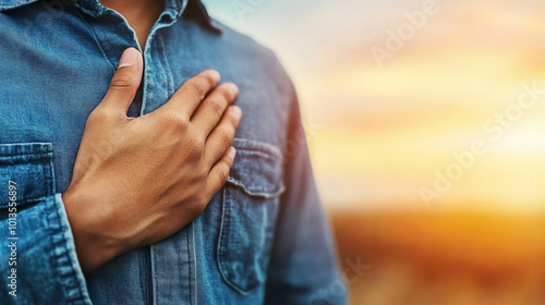 person in denim shirt places hand over their heart, symbolizing sincerity and emotion