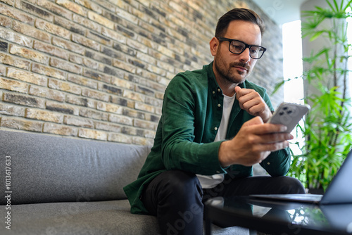 Low angle view of manager using online applications over smart phone while sitting on sofa in office