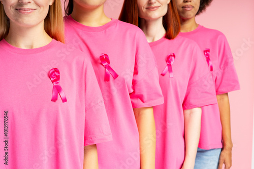 Diverse women wearing pink t shirts with ribbons supporting breast cancer awareness