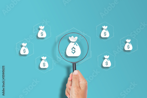 Magnifying glass focuses on icon of money bags savings and investment concept, diverse financial assets, invest money