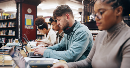 Education, laptop and typing with student friends in library of university together for learning or study. Computer, development or growth with serious men and women on college campus for scholarship