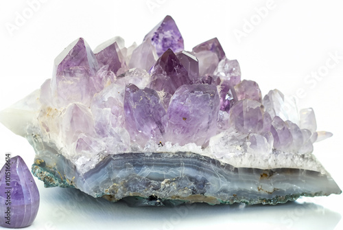 Close-up of a raw amethyst geode crystal with purple and clear quartz formations, isolated on a white background.