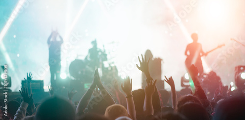 nightlife, stage, concert, music, music festival, musician, entertainment, act, applauding, cheer. A crowd of people are at a concert, with the band on stage and the audience cheering.