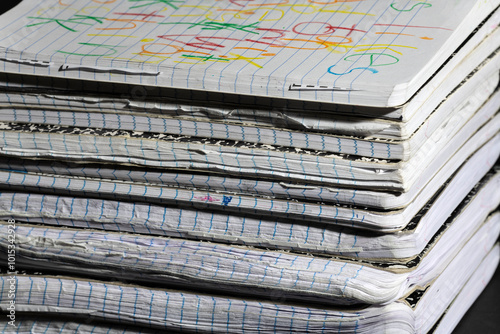 Stack of Worn Notebooks. A stack of well-used notebooks with worn edges and colorful scribbles on the top cover, showcasing creativity and everyday use. Ideal for education or writing-related themes.