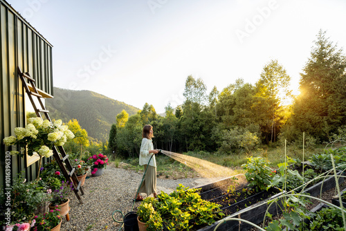 A woman waters her garden in the early morning, surrounded by lush greenery and a stunning mountain view. The peaceful moment captures the essence of life in harmony with nature