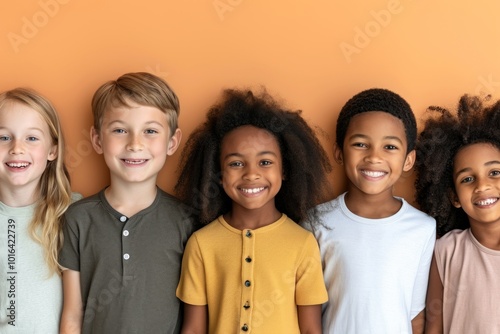 Group of happy kids standing together and looking at camera on orange background