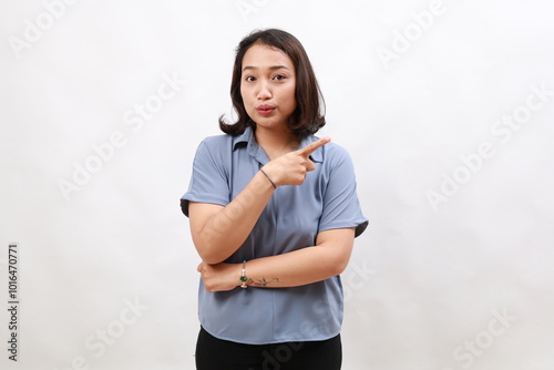 Portrait of asian business woman, looking impressed and showing advertisement, pointing fingers right, standing over white background